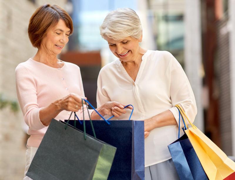 Two older women shopping and walking with shopping bags.