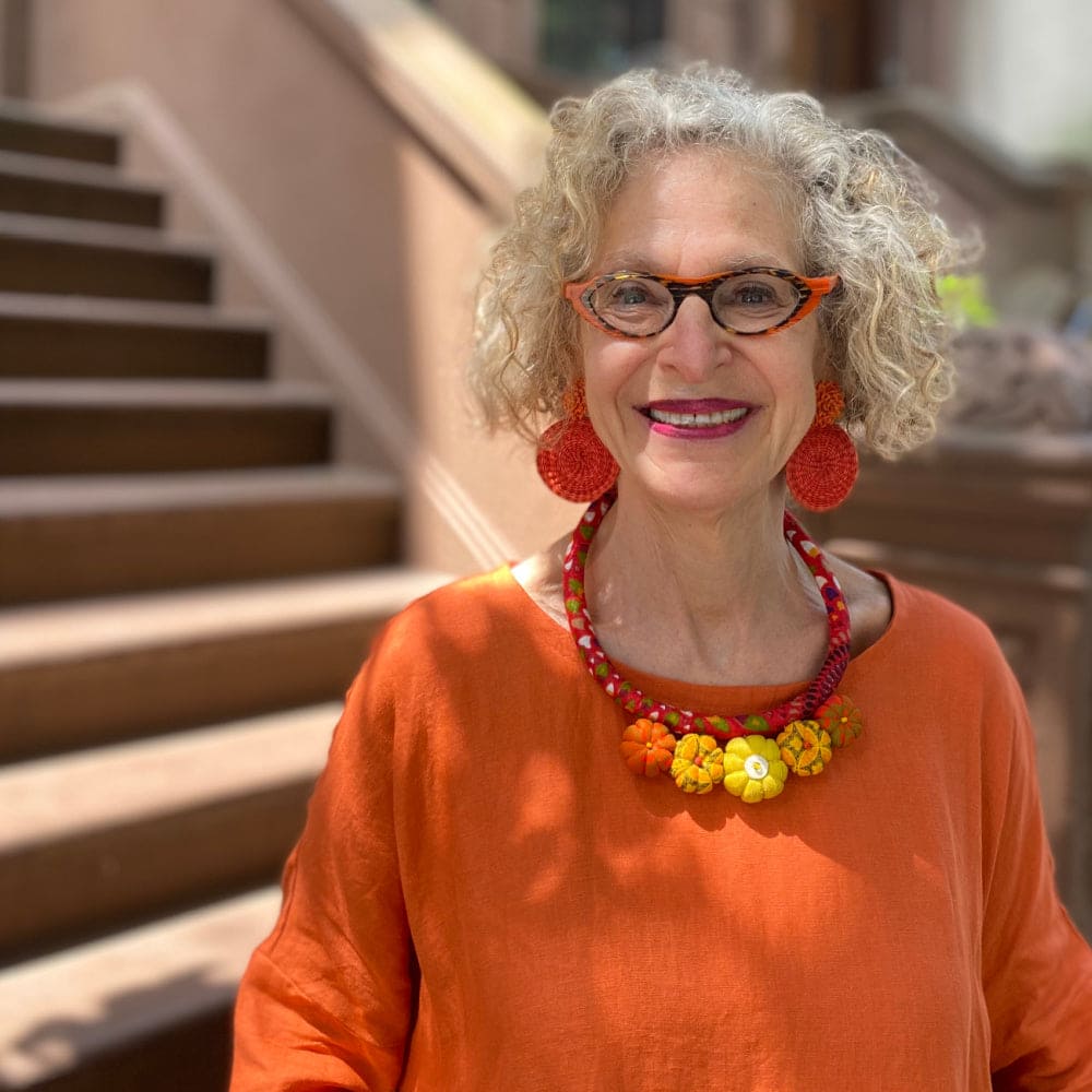 Colral red and yellow textile necklace with Iraca earrings worn on a smiling older woman.