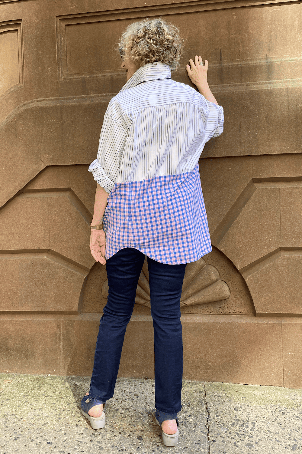 Back view of stylish older woman wearing a two print upcycled shirt with slim jeans.