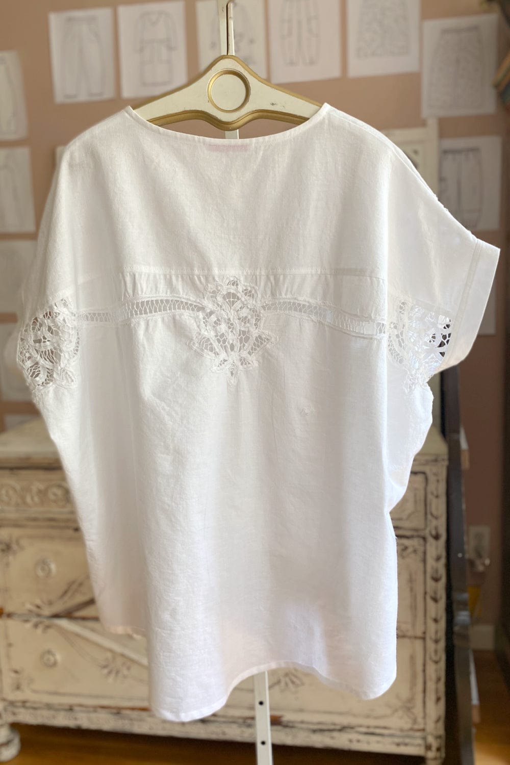 Back view of a women's white cotton shortsleeve top with decorative stitching.