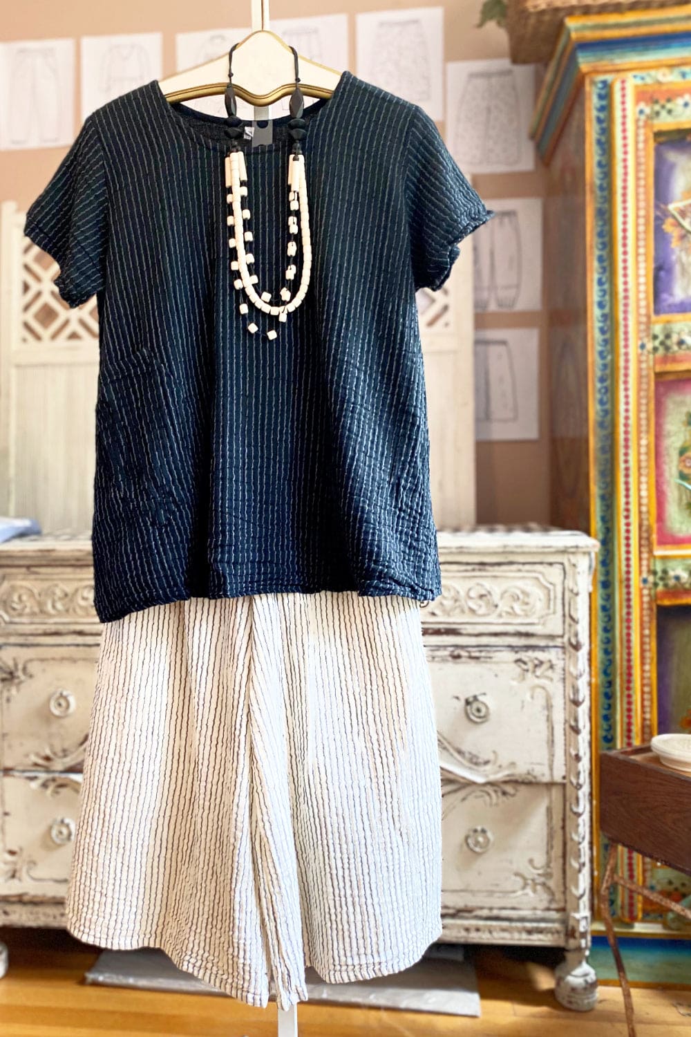 Women's short sleeve aline shaped cotton tee paired with full cut cotton creme pants and funky wooden necklace.