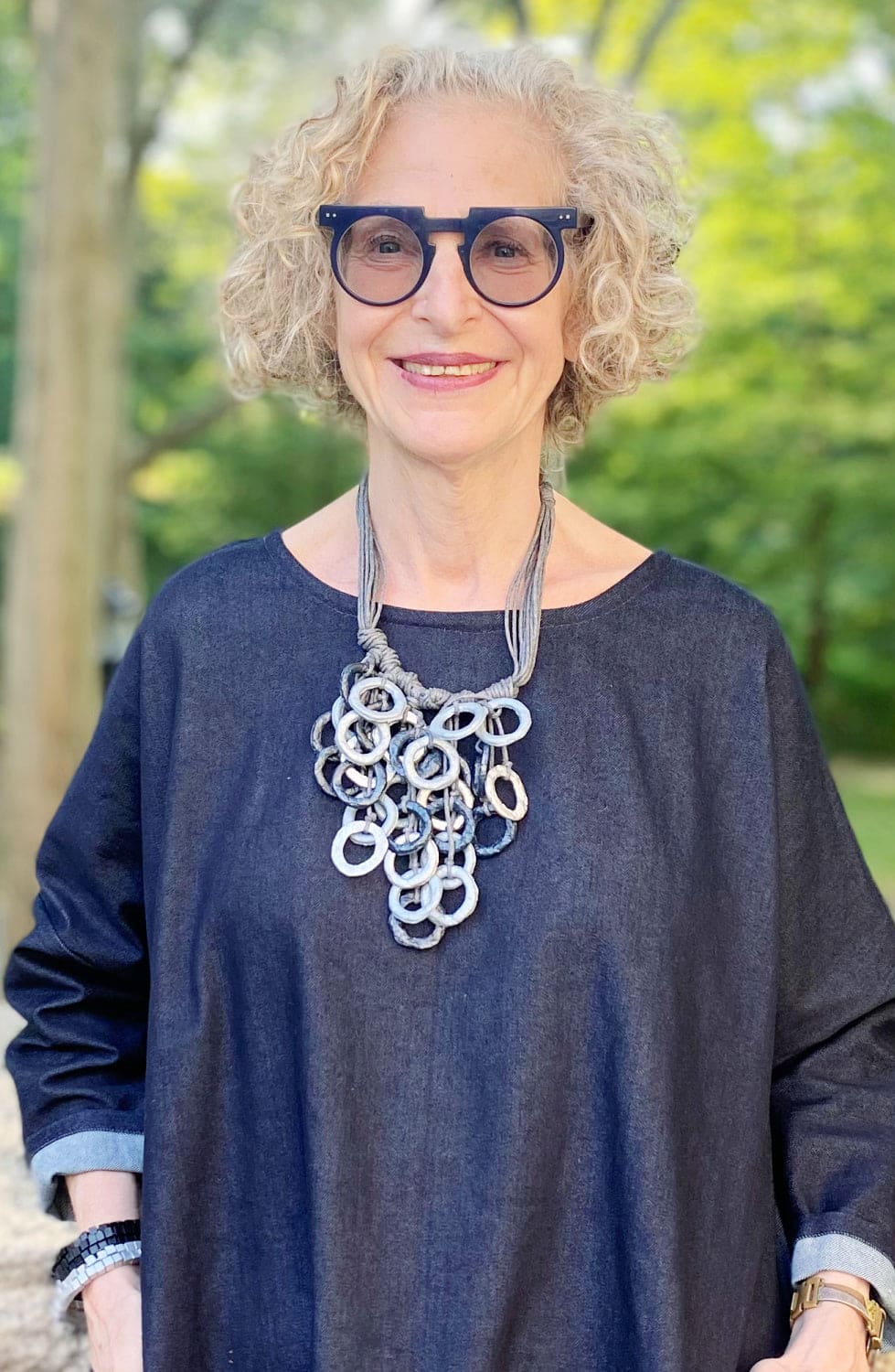 Multiple grey tones necklace worn with a denim loose fit dress.