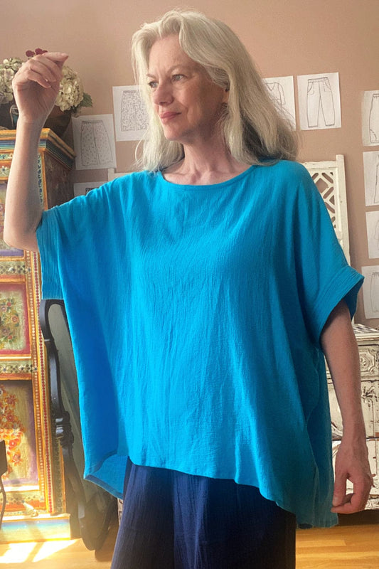 Srop sleeve soft cotton tee in a beautiful turquiose worn on a woman with long grey hair.