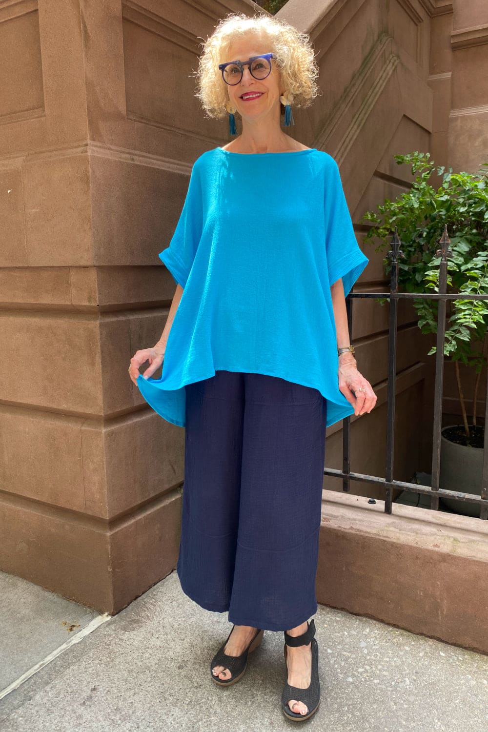 Loose fit cotton navy pants worn with a bright turquoise elbow length sleeved tee.