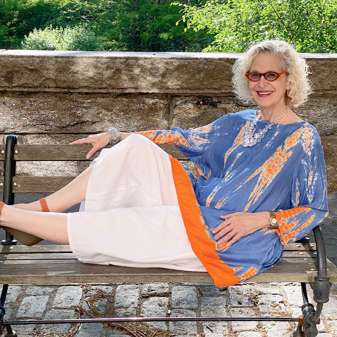 Tie Dye Top in pretty blue and orange worn on an older woman. She is wearing a pair of loose fit white cotton pants.