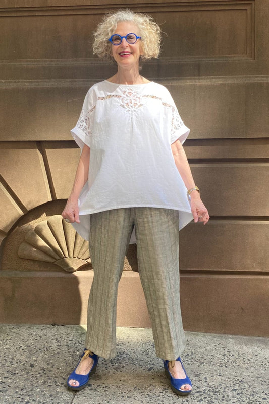 Smiling older woman wearing loose fit plaid linen pants with a vintage tablecloth shortsleeve top.