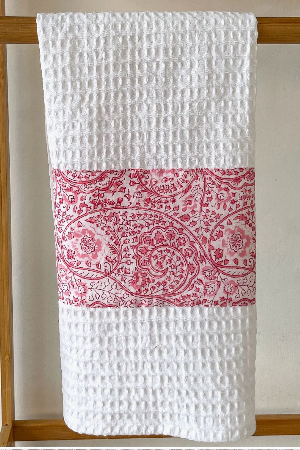 White cotton tea towel decorated with red handblocked pattern.