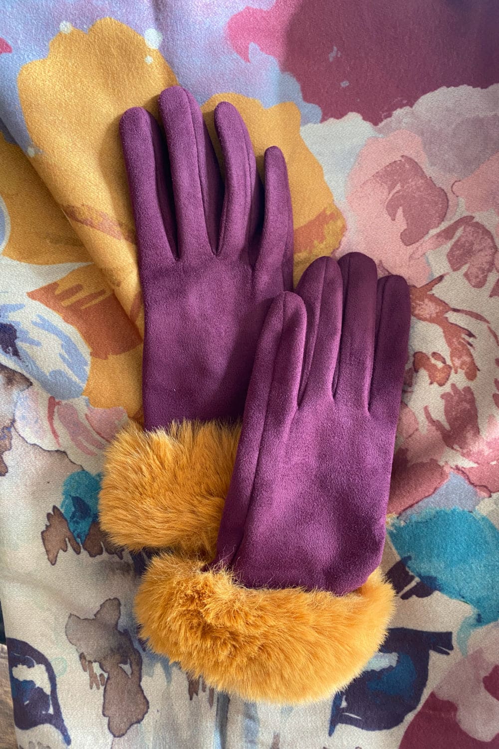 Purple and Mustard faux fur gloves laying ontop of matching multi colored scarf.
