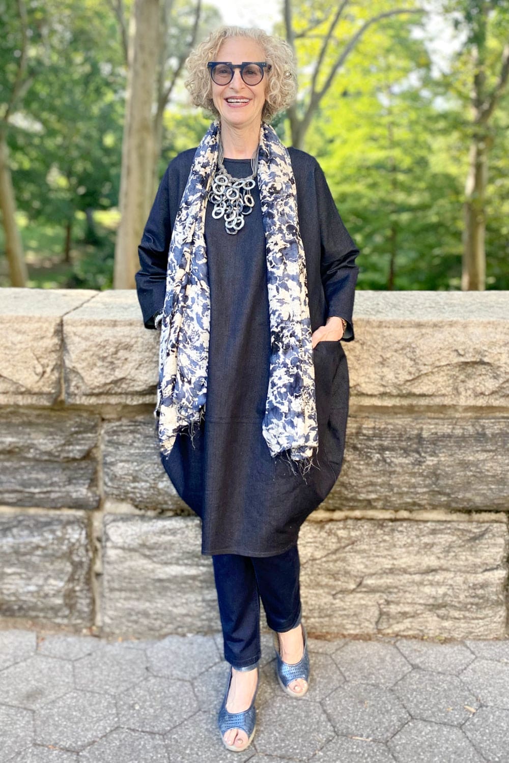 Cheerful indigo splatter pattern silk scarf worn on smiling older woman.