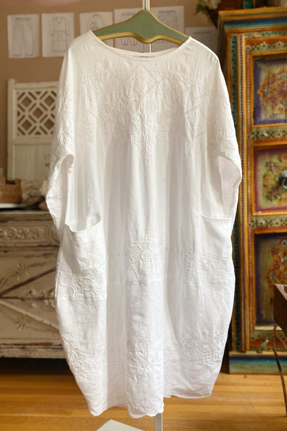 Cotton white bubble shape dress with delicate stitching detail. It has a round neckline and two front pockets and hanging from a vintage hanger.
