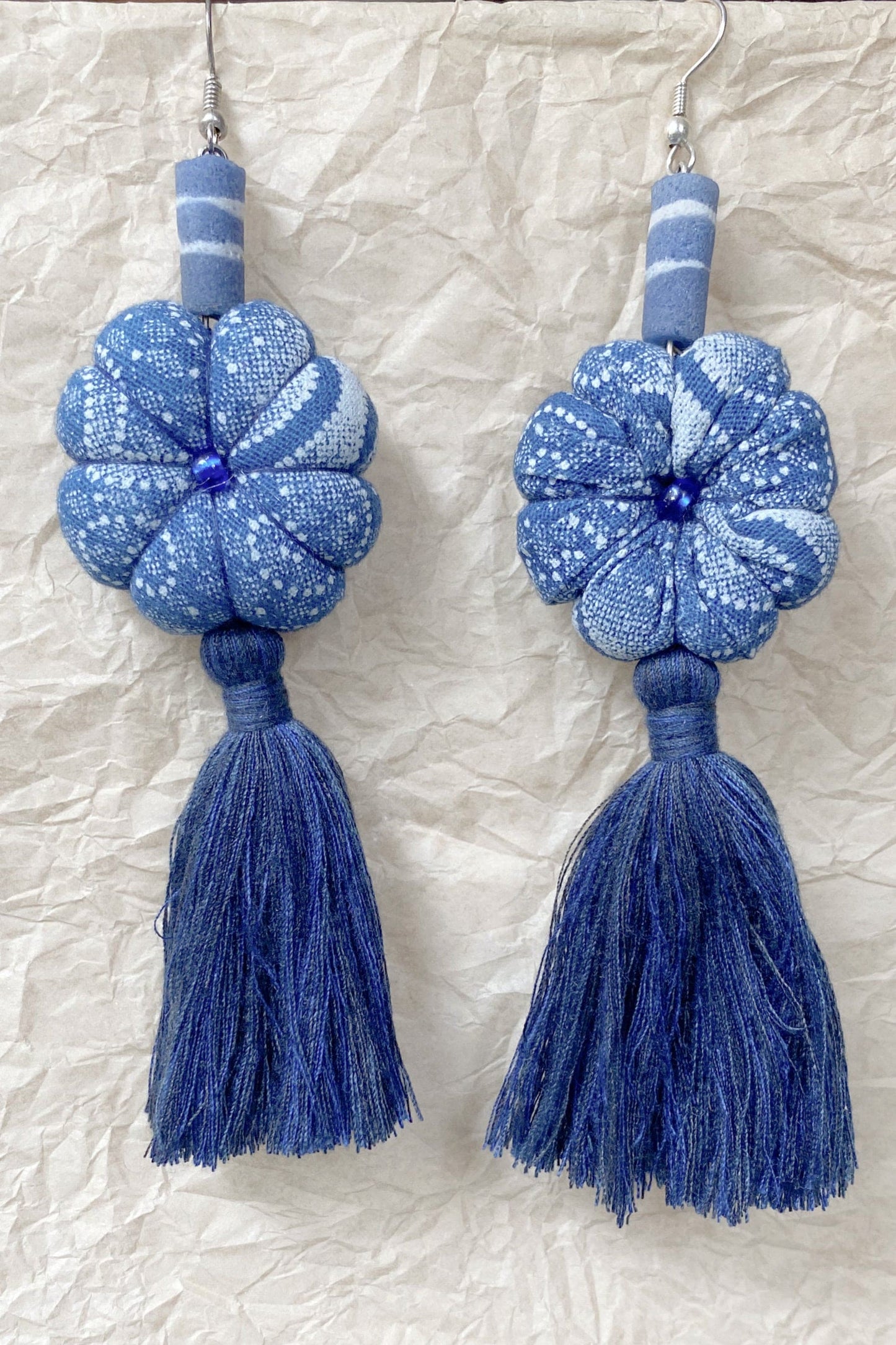 Handcrafted tassel earrings white pattern on blue.