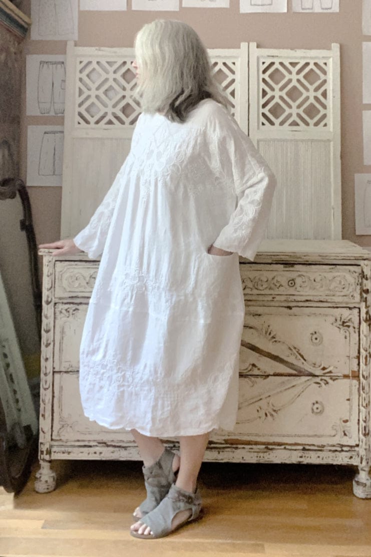 Cotton white bubble shape dress with delicate stitching detail. It has a round neckline and two front pockets.