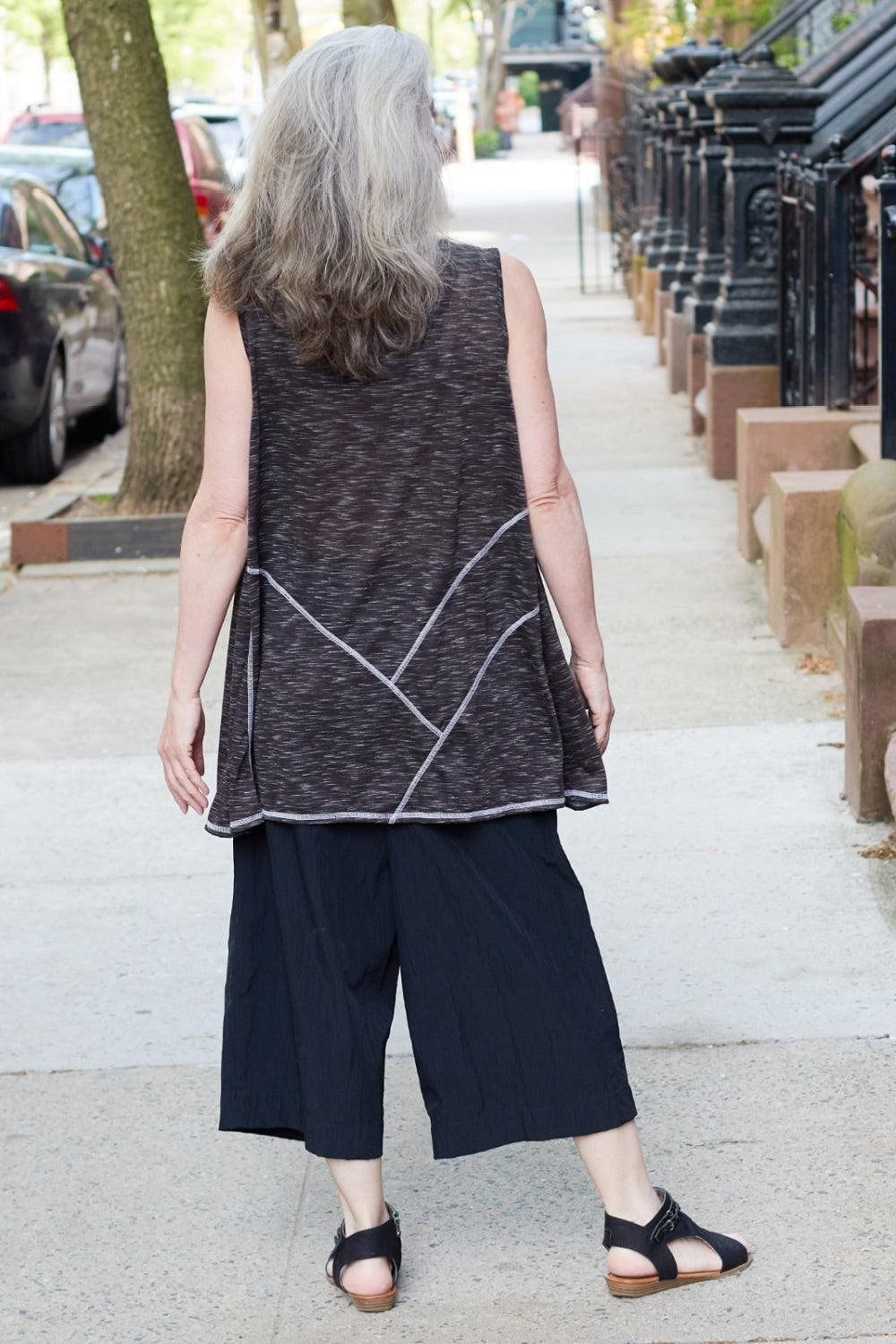 Back view of Long Grey hair woman wearing a Grey Fleck Aline Tank with full cut black crop pants walking on the street