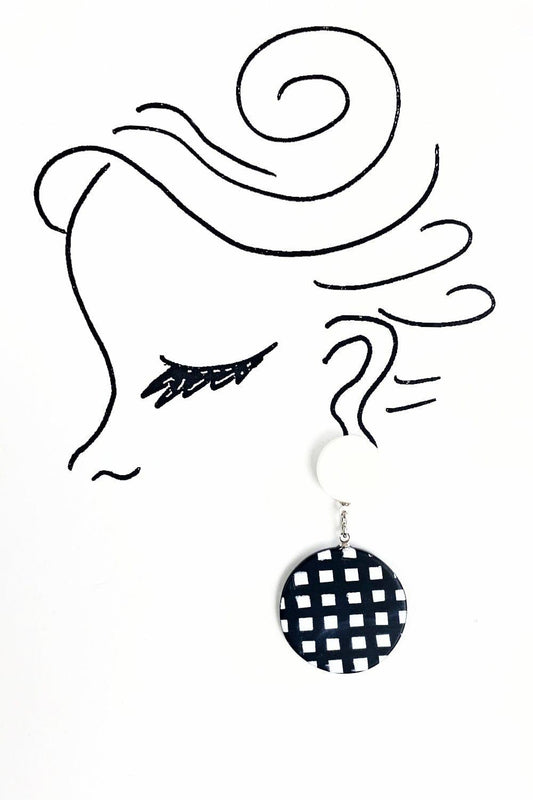 Black and white checker round shaped earrings hanging from a smaller white post. 