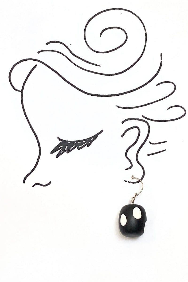 Black with White Polka Dots Earrings shaped round and smooth surface. French hook, and earring is dangling from an artist rendering of a woman's profile
