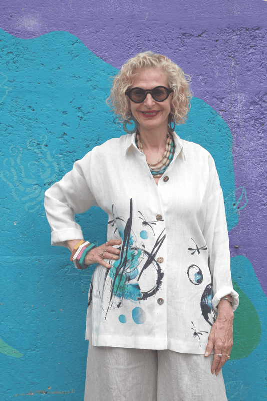 Woman wearing a linen button down shirt with a dragon fly print.
