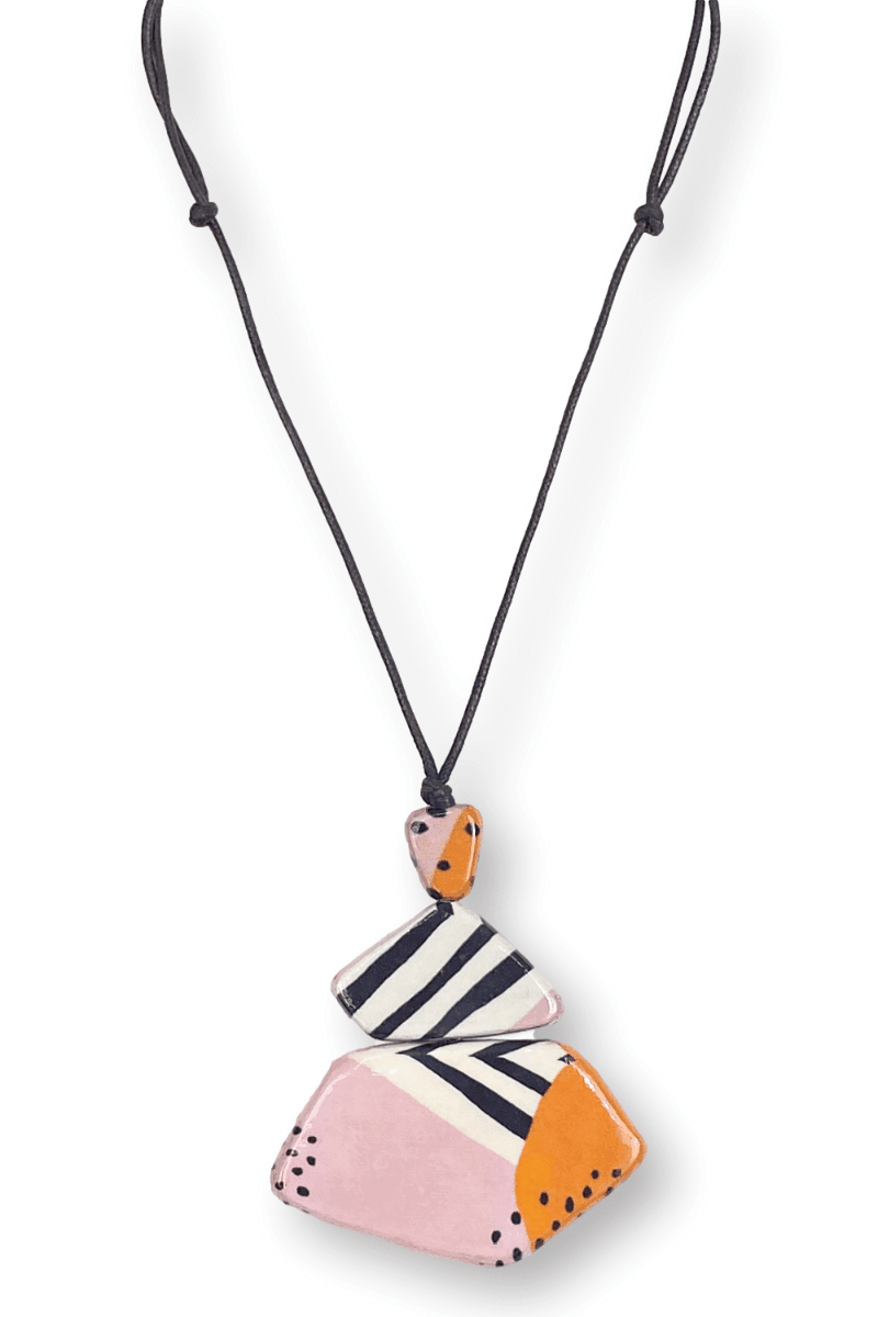Three tier wooden pendant neckacle with black and white stripes and dots. Flat wooden beads stacked from small to large and strung on an adjustable black cord.