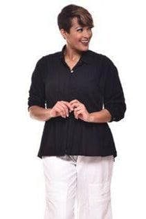Smiling woman with short brown hair wearing a black seersucker cotton button down blouse with white loose fit cotton pants.