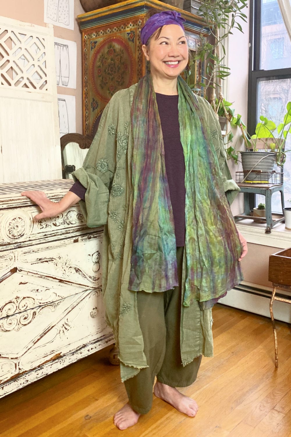 Long cotton duster jacket worn with silk scarf and linen crop pant. The outfit is green and purple.