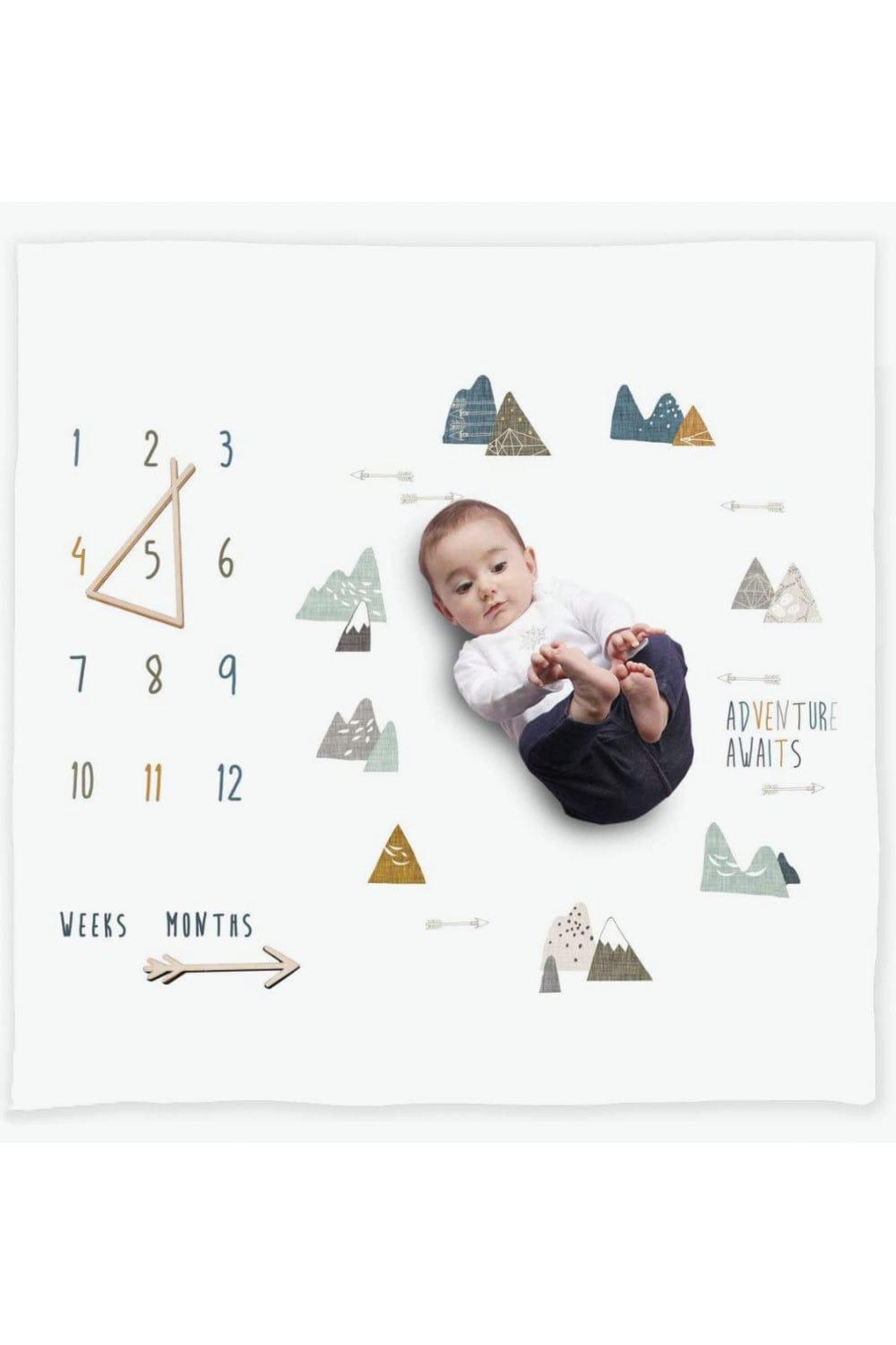 Sweet baby playing on a milestone blanket with a mountain adventure motif.