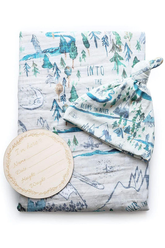 Baby swaddling blanket designed in a forest motif with a matching hat and birth anouncement card.