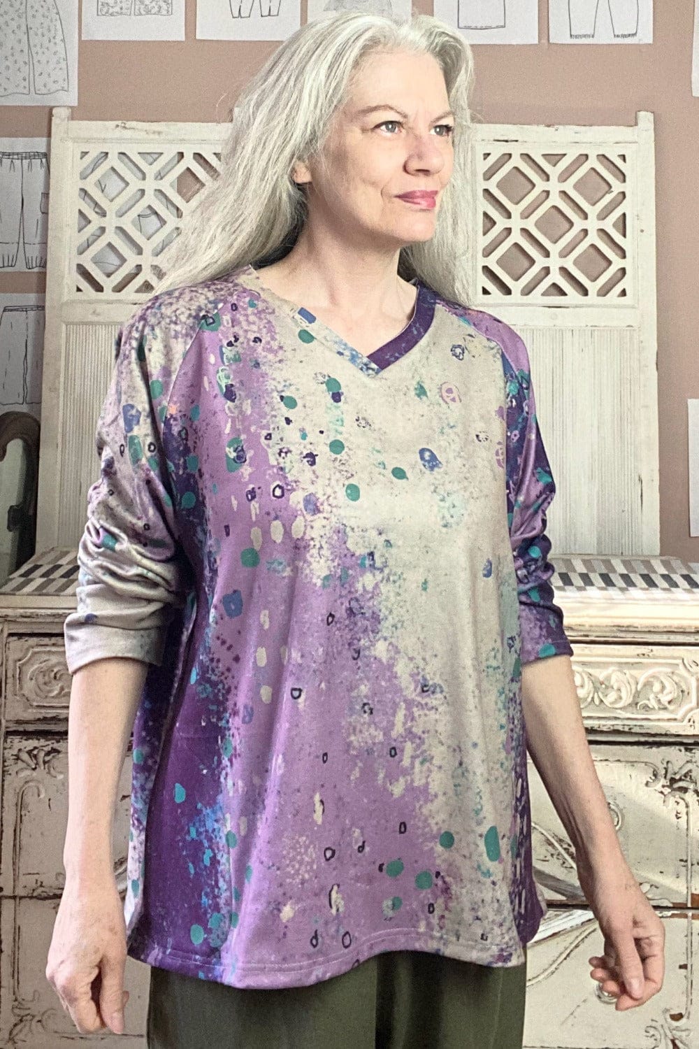 V neck women's sweater with spottoned purple design worn on a woman with long grey hair.