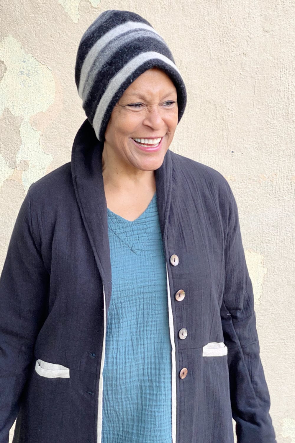Merino wool cap with grey and black stripes worn on a smiling woman.