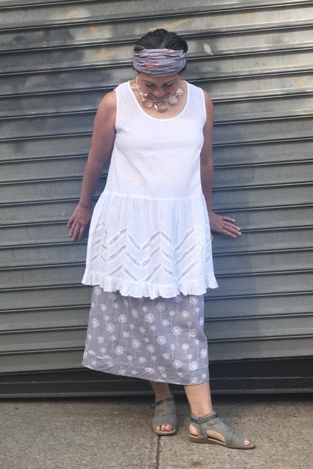 Sweet grey and white cotton skirt with a dandilion print worn on a woman aslo whereing a cotton sleeveless tunic with cutouts.