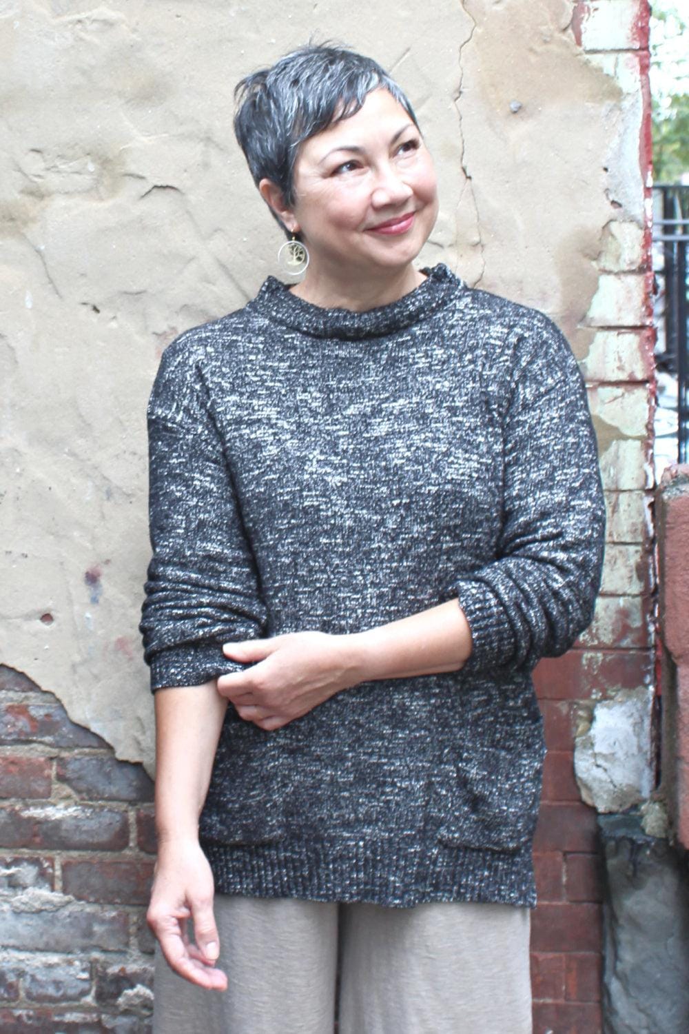 Smiling woman with cropped grey hair wearing a HighNeck Pullover in a grey fleck.-
