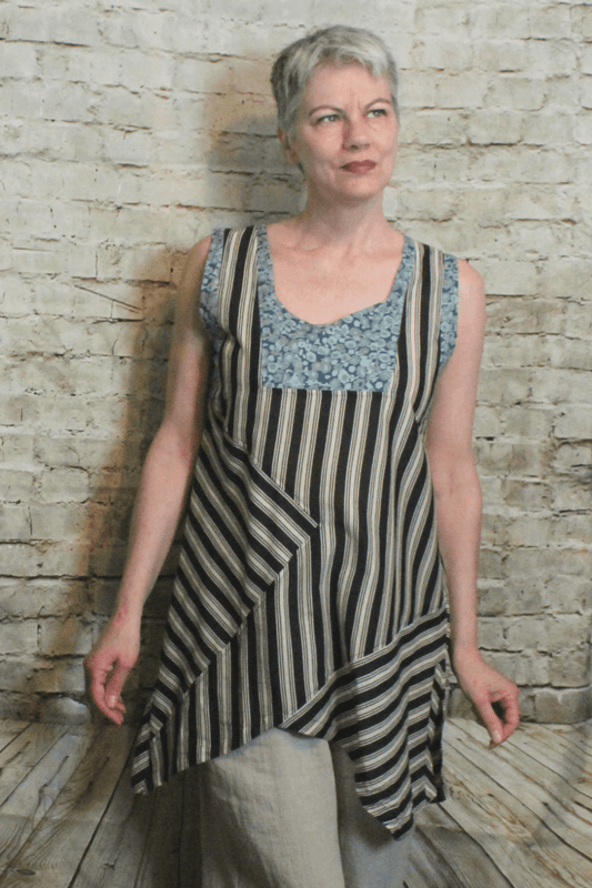 Woman with short grey hair wearing a sleeveless cotton tank. Blue floral pattern mixed with taupe and black stripes. 