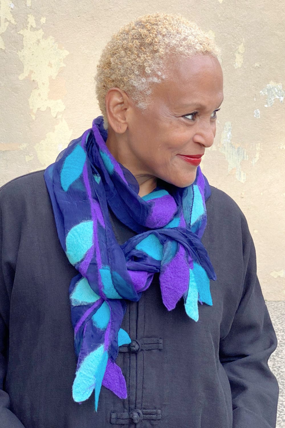 Merino Wool and Silk Chiffon Scarf designed in a leaf motif. Pretty purples and blues. Worn on an older woman wearing a black linen jacket.