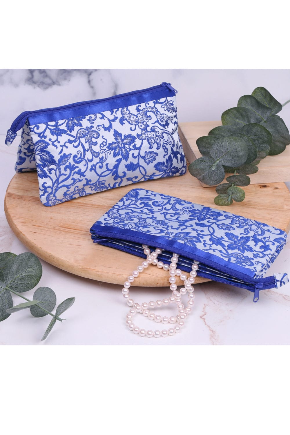Tapestry Blue and white 3 section makeup bag with top blue zipper.