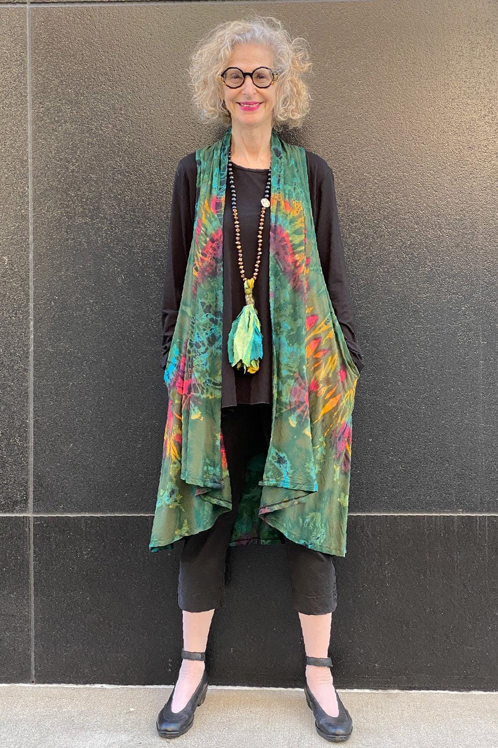 Tie Dye vest in greens and spashes of color worn with a long statement necklace with green fabric.
