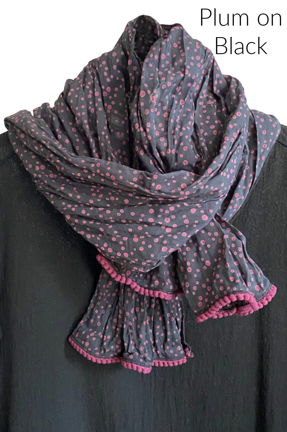 Pretty cotton scarf with plum dots and trim with a black background. print. Edges are trimmed little textured trim.