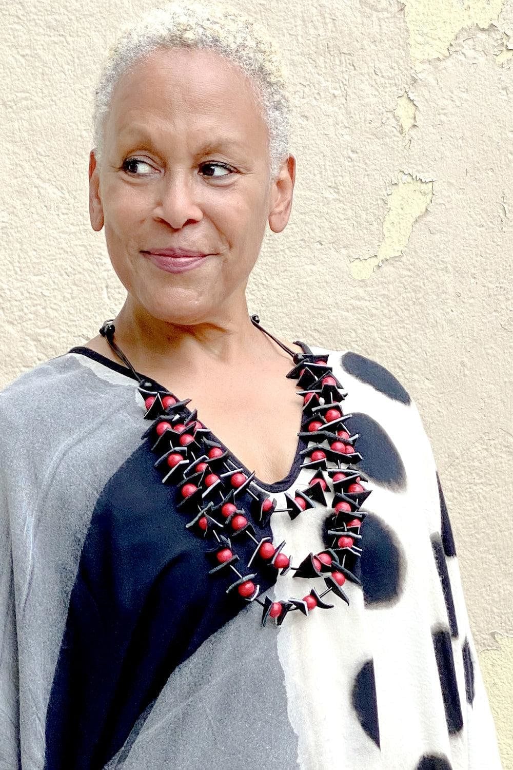 Smiling woman wearing a Red Multi Strand Necklace with a graphic v neck tunic.