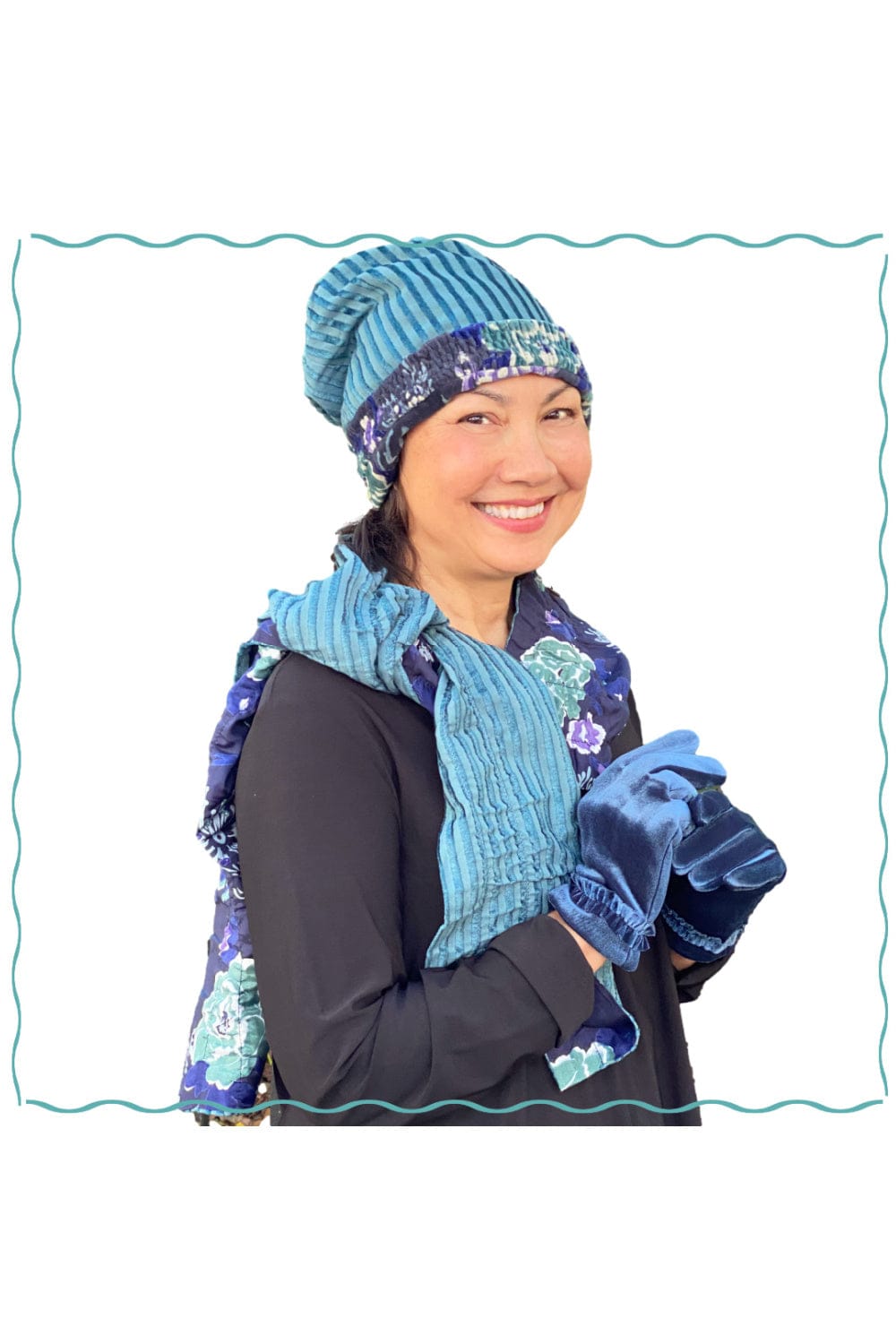 Reversible hat and scarve in a pretty blue floral and stripe design. Smilling model wearing blue velvet gloves and a black long sleeve tee.