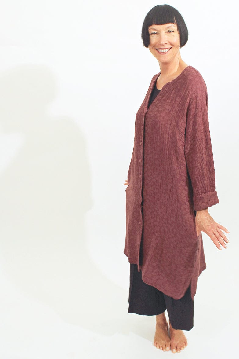 Womens rose colored long textured linen jacket with fabric covered front buttons and side pockets.