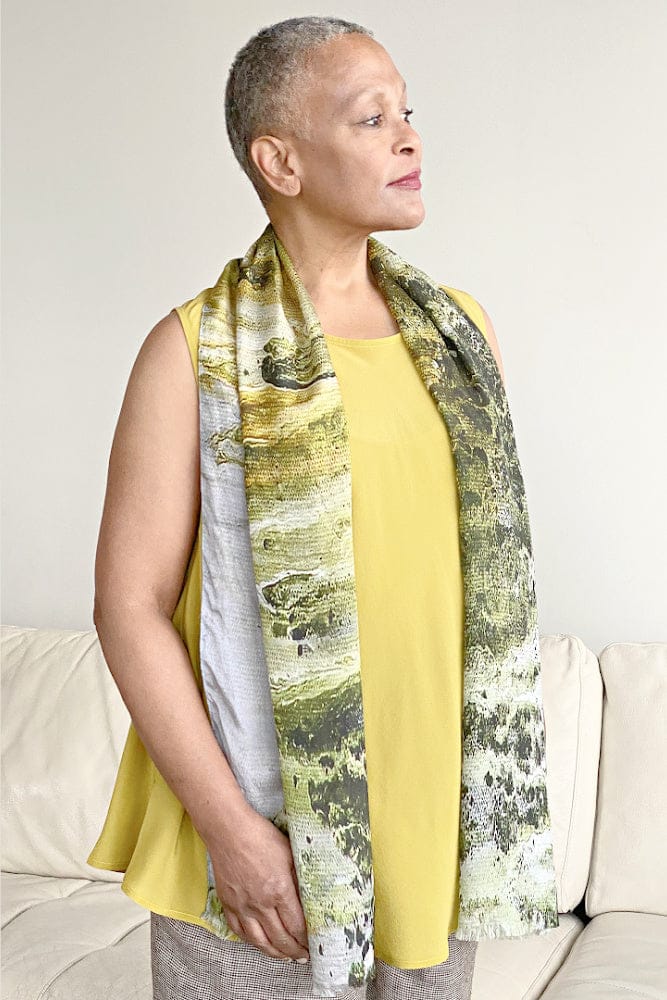 Moss green and grey silk pebble rectangle scarf worn over a soft mustard color silk tank. Worn on an older woman with cropped grey hair.