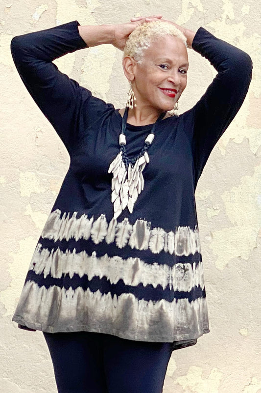 Long sleeve black swing top with tie dye design. Smiling older woman wearing a necklace made with recycled paper.