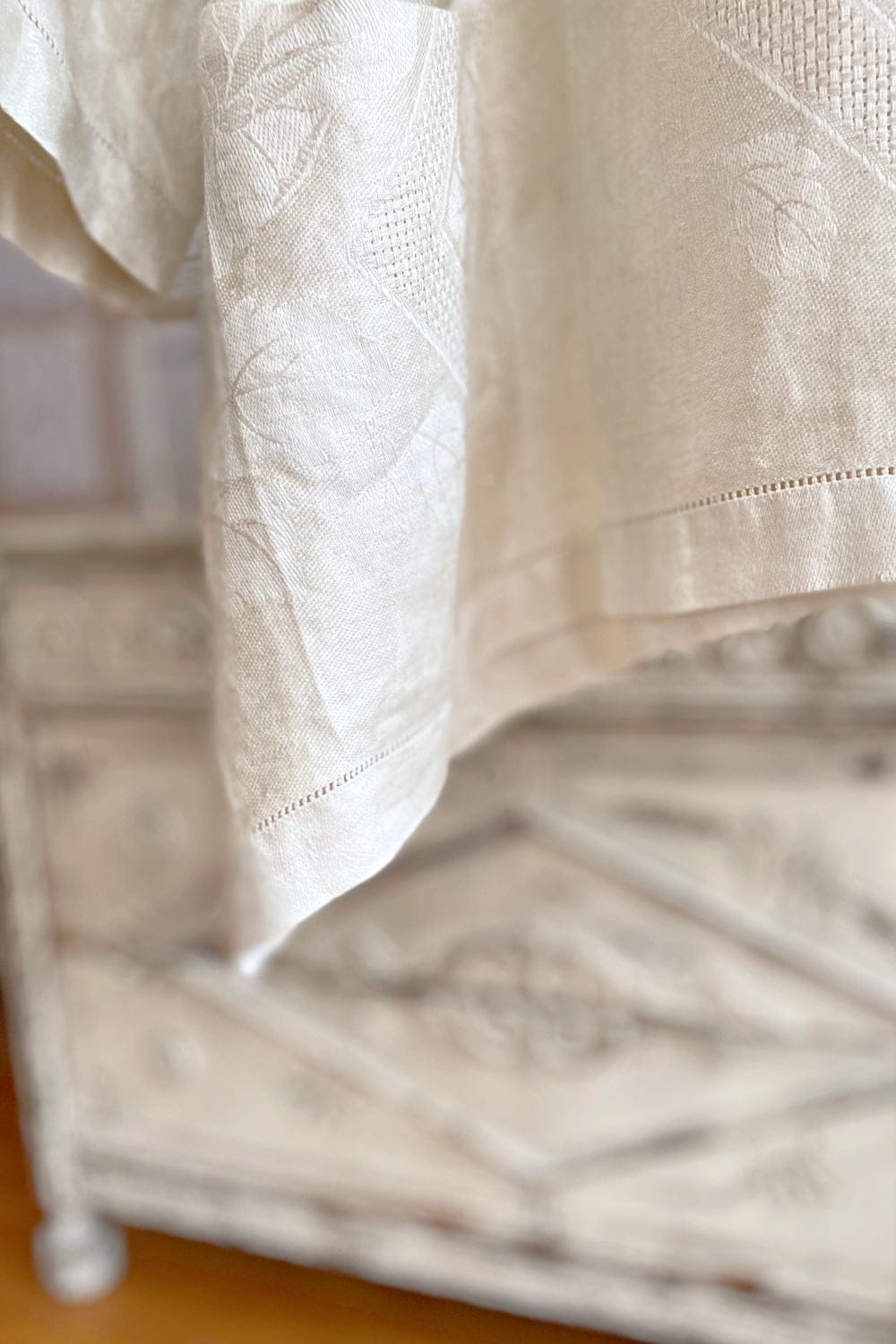 Hemline detail of Upcycled linen tablecloth women's two pocket aline shape onesize blouse displayed on vintage hanger.