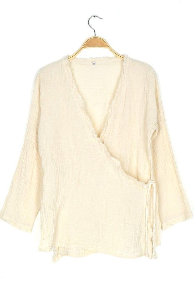 Natural Colored Gauzy looking textured cotton crossover longsleeve women's top hanging from a hanger.
