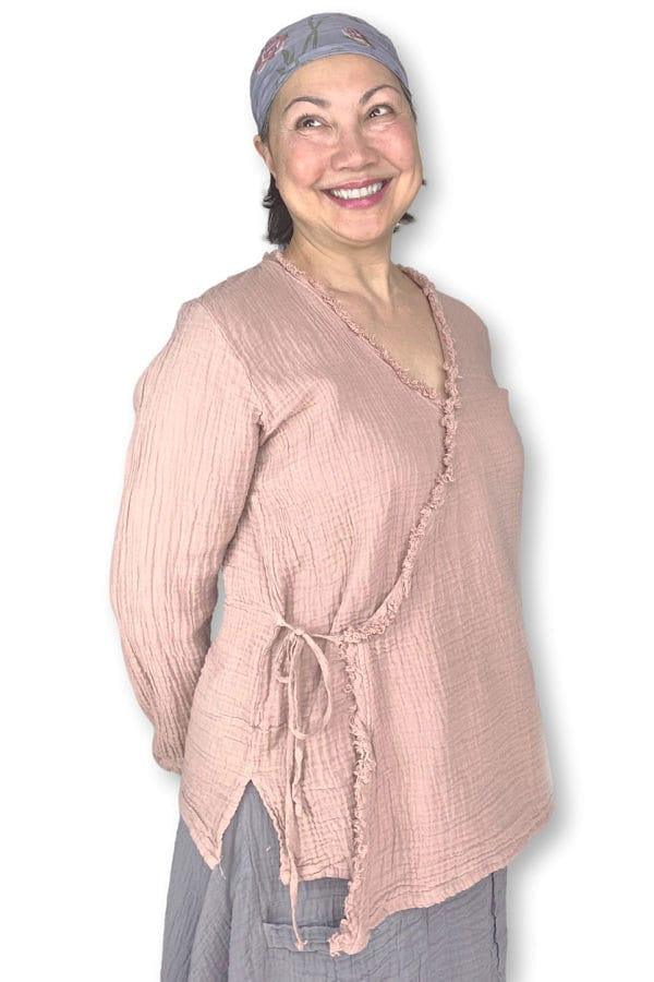 Woman 0ver 50 years older wearing soft pink cotton long sleeve wrap blouse with a loose fit long grey cotton skirt with front pockets